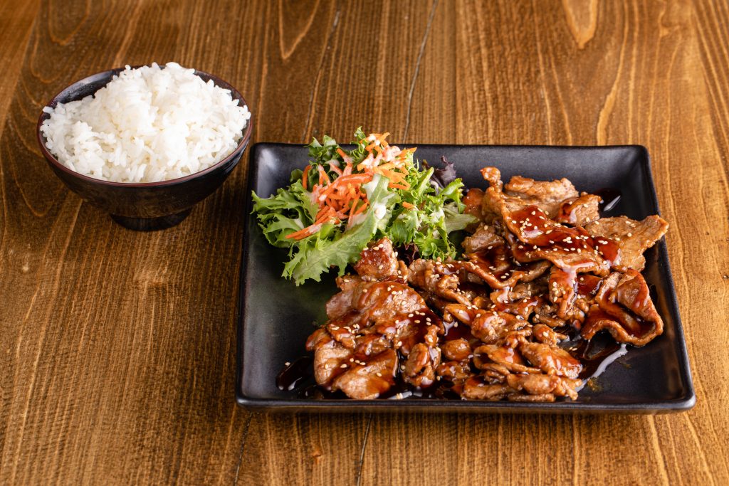 Stir fried beef with teriyaki sauce, a side of rice and a salad