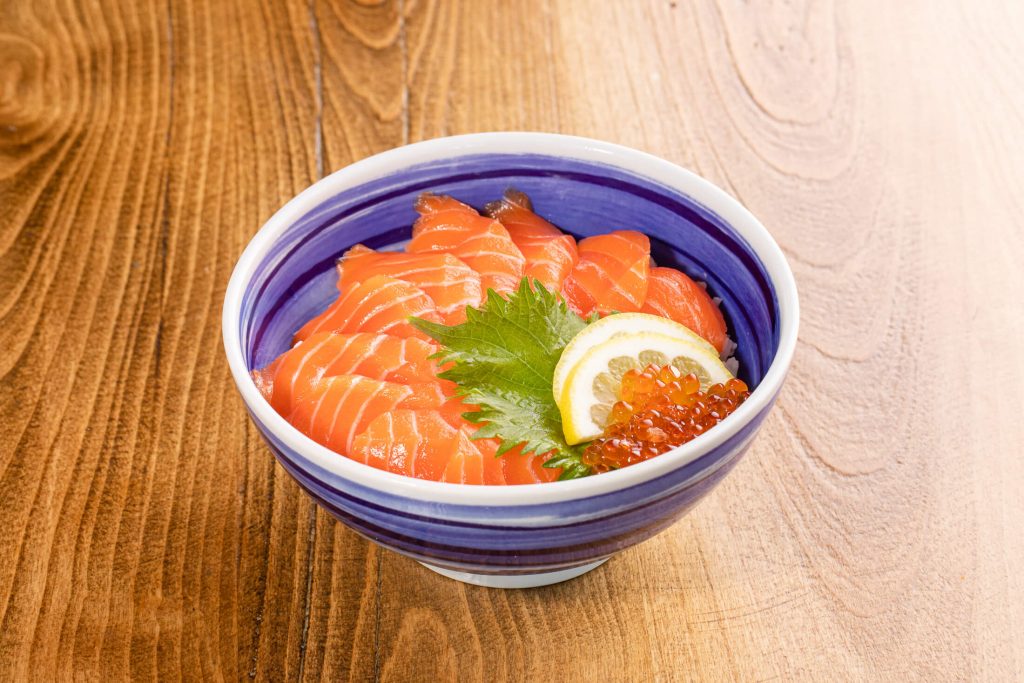 Slices of raw salmon over sushi rice
