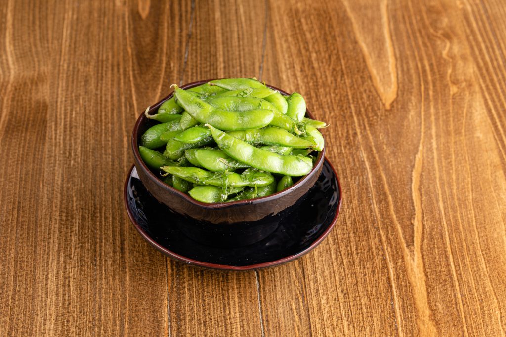 A bowl of edamame covered in garlic, lemon, cilantro, butter