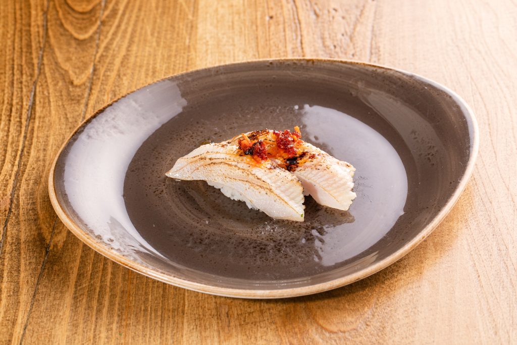 Two Yellowtail torched, truffle wasabi sauce, balsamic, ponzu, chili garlic almond sauce nigiri