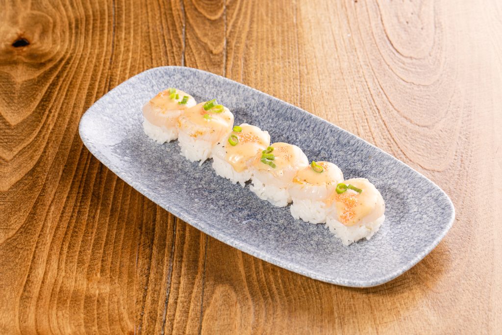 Lightly seared rare scallops on top of rice cubes, scallop sauce, masago, green onion