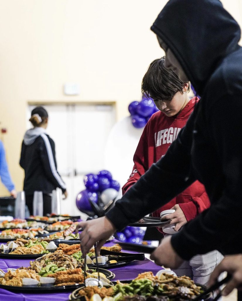 Person in hoodie picking food from platter
